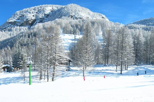Una montagna innevata con piste da sci e un rifugio.