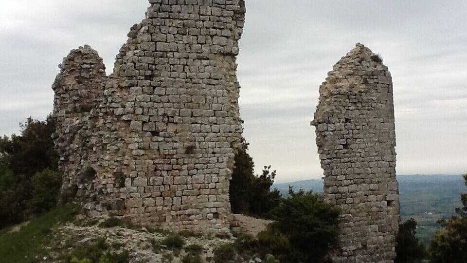 Ancient stone ruins with two prominent towers and a partially intact wall.