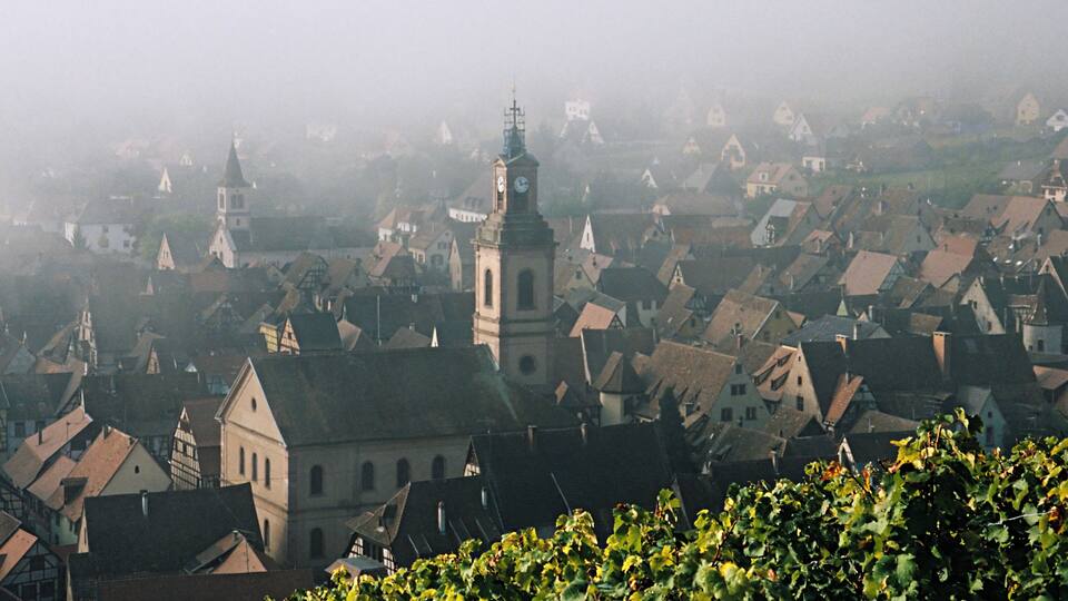A foggy view of a town with historic buildings and a prominent church tower.