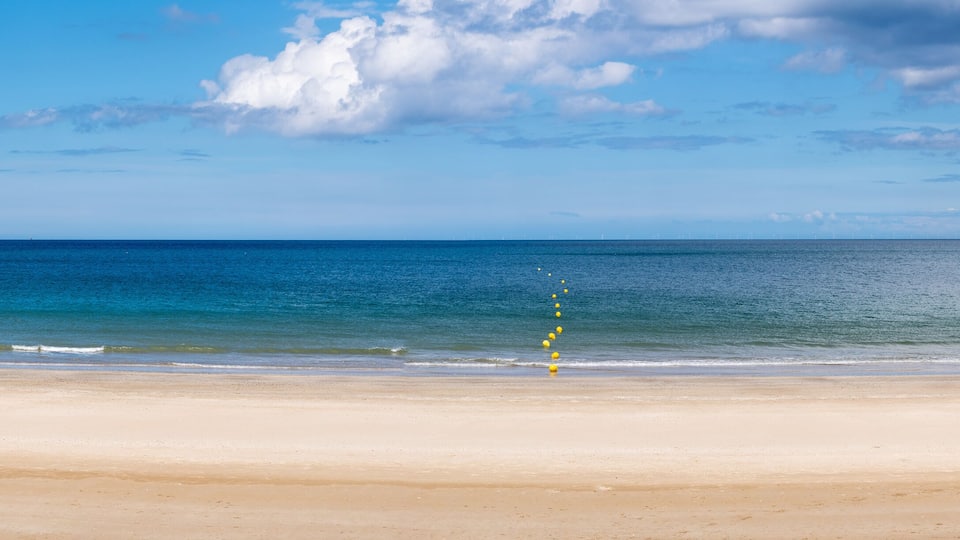 A beach with a clear sky and calm sea.