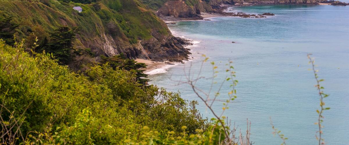 Un paysage côtier avec des falaises, une plage et des maisons situées sur le versant de la colline.