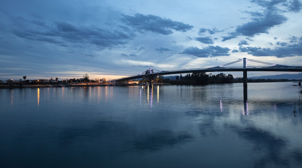 Eine BrĂŒcke ĂŒber ruhigem Wasser unter einem DĂ€mmerhimmel.