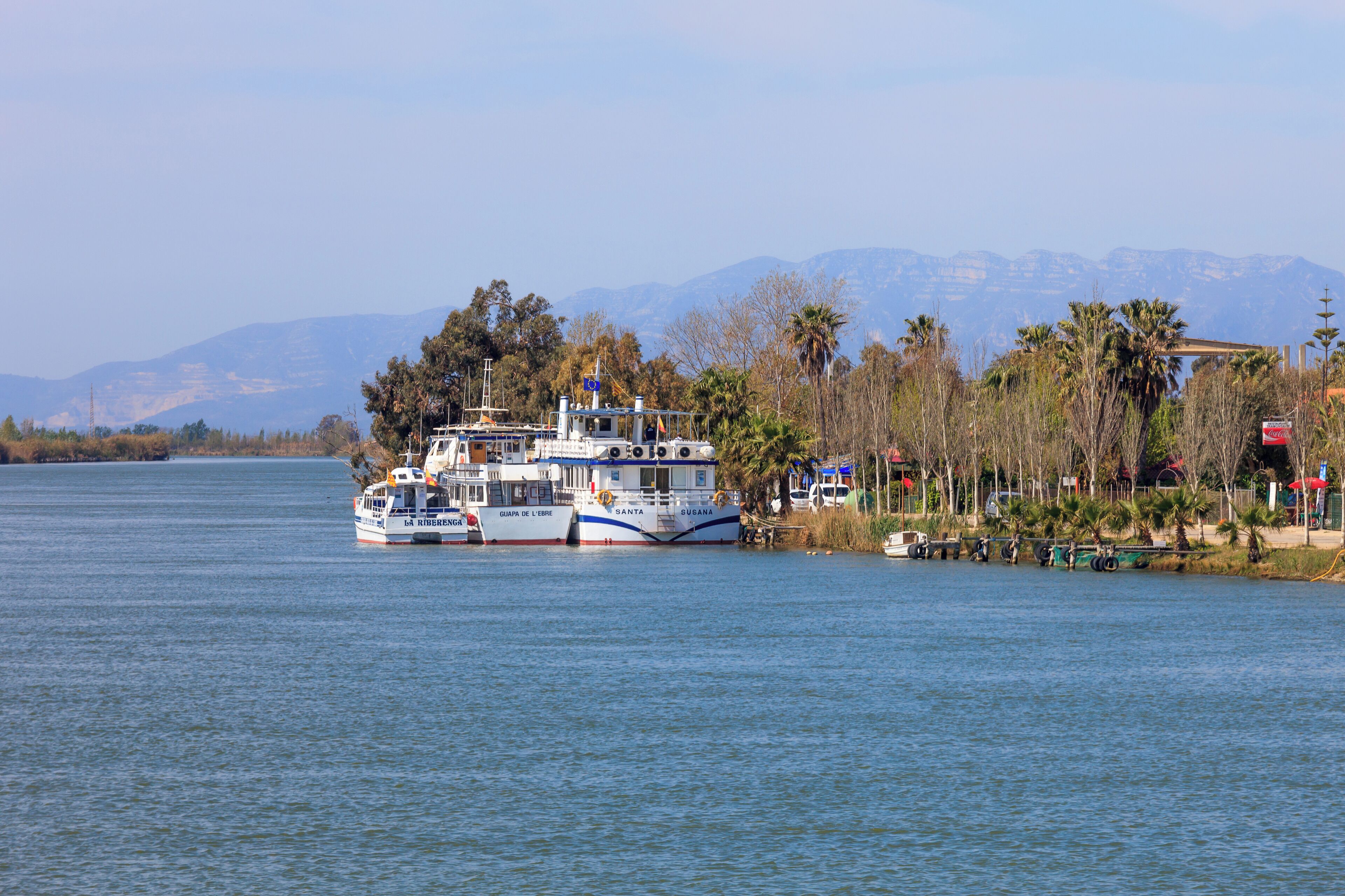 A ferry boat named 'SANTA' on a calm lake with mountains in the background.