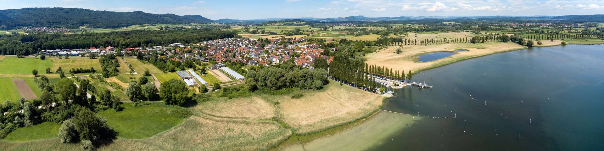 A lakeside town with a river, surrounded by fields and hills.