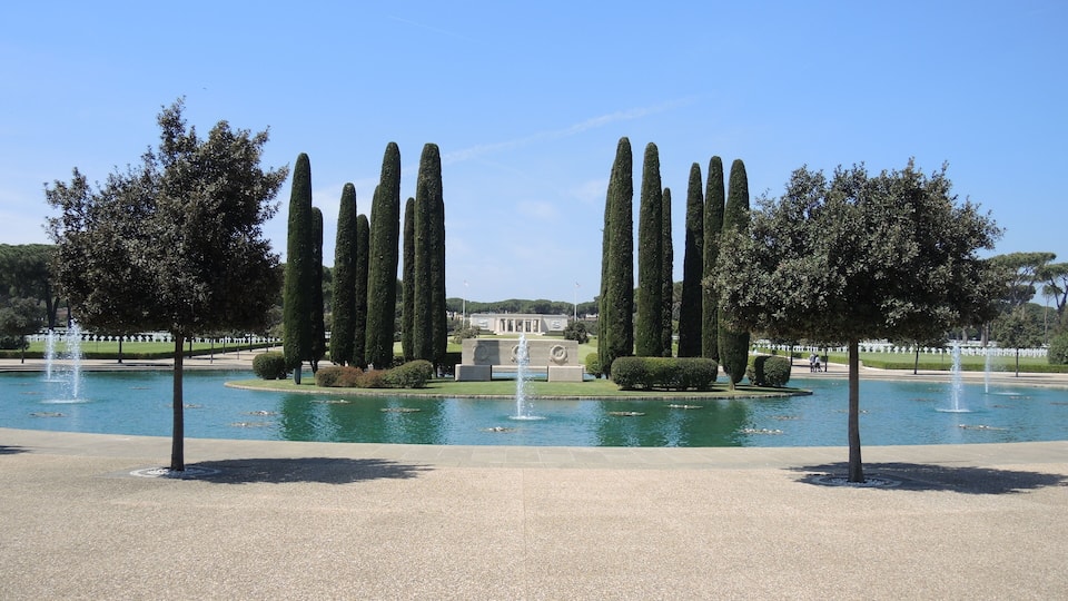 A formal garden with a central fountain, tall cypress trees, and a symmetrical layout.