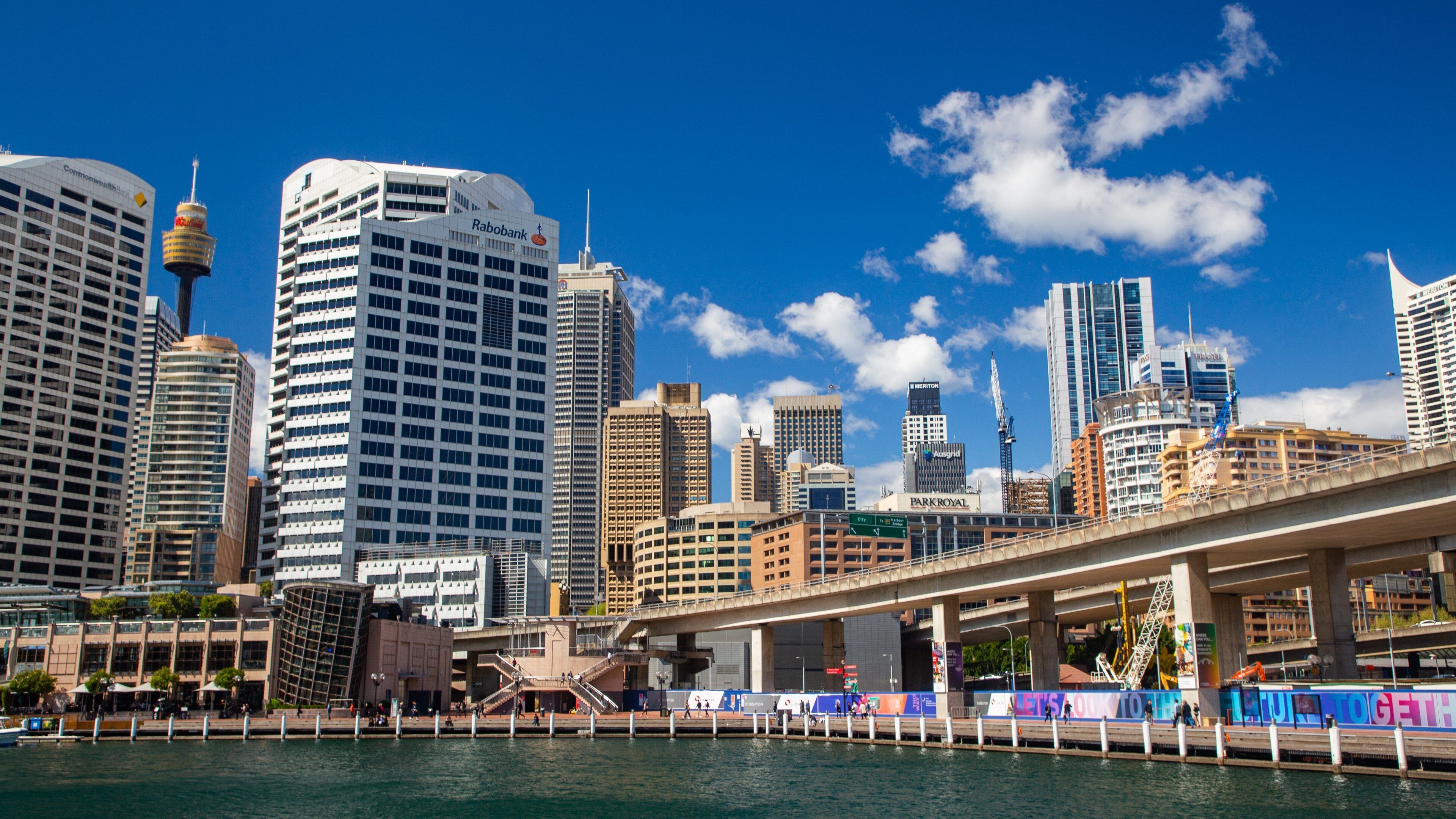 A city skyline with modern skyscrapers, a prominent tower, and a waterfront promenade.