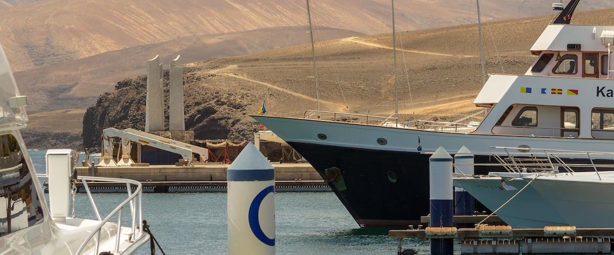 A boat docked at a harbor with mountains in the background.