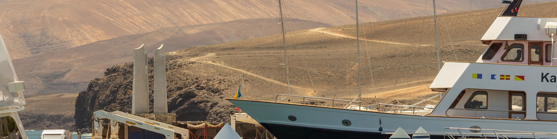 A boat docked at a harbor with mountains in the background.