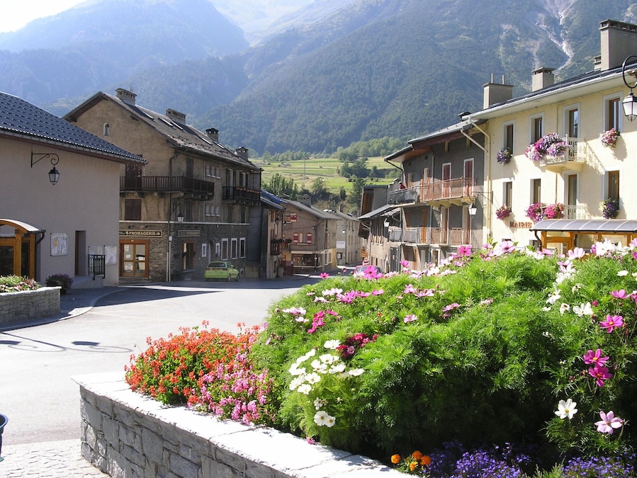 Ein Bergdorf mit bunten Blumenbeeten und traditioneller Architektur.