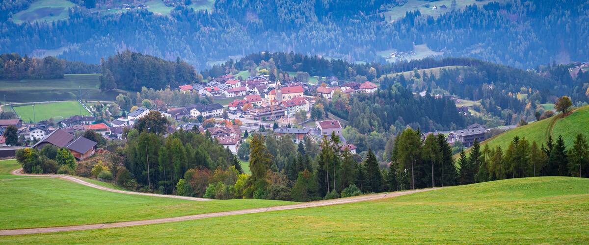 A village nestled in a valley surrounded by forested hills.