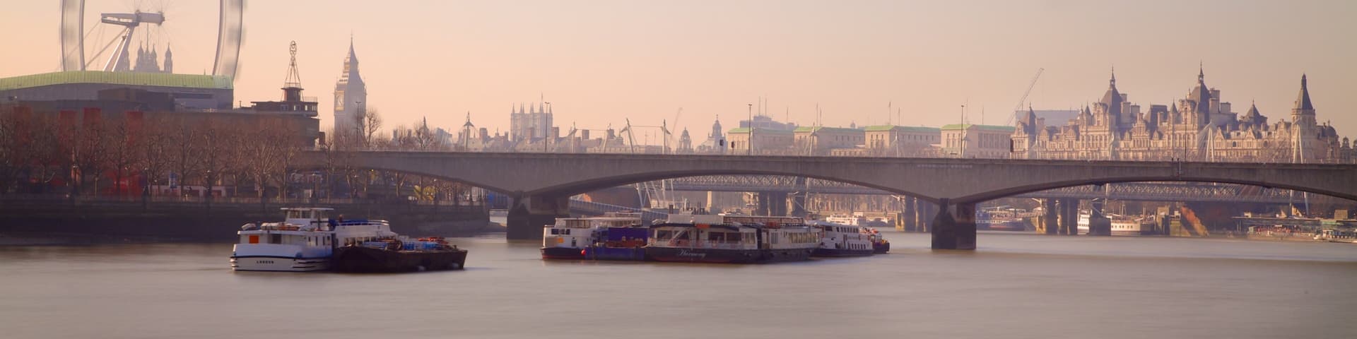 A river with boats, a bridge, and the London Eye in the background.