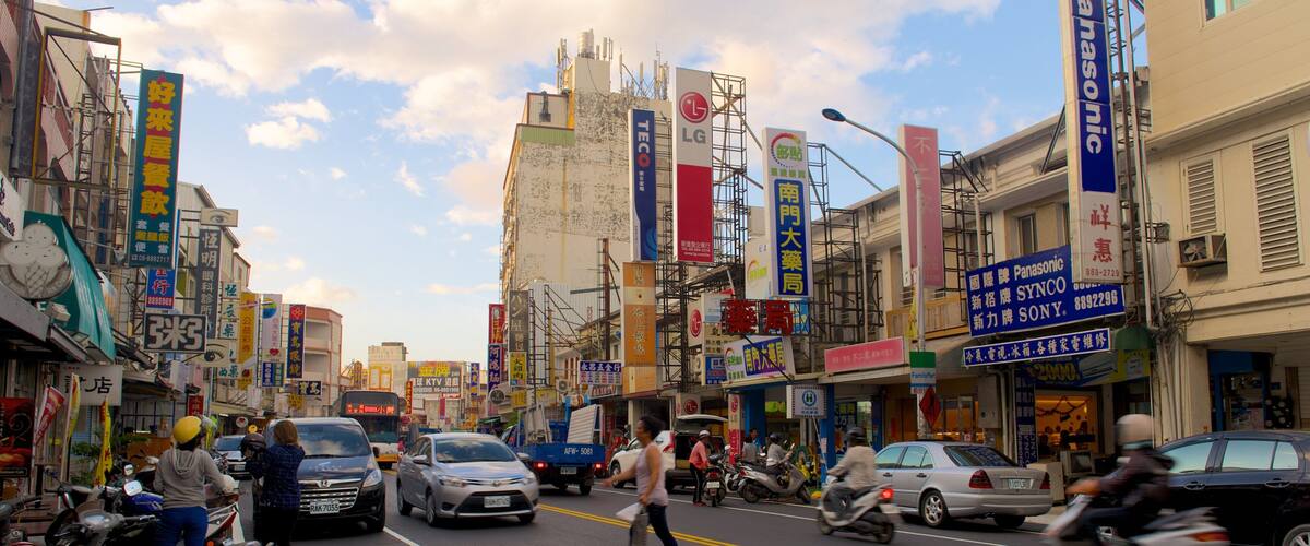 A busy urban street with various commercial signs, including Panasonic and LG.
