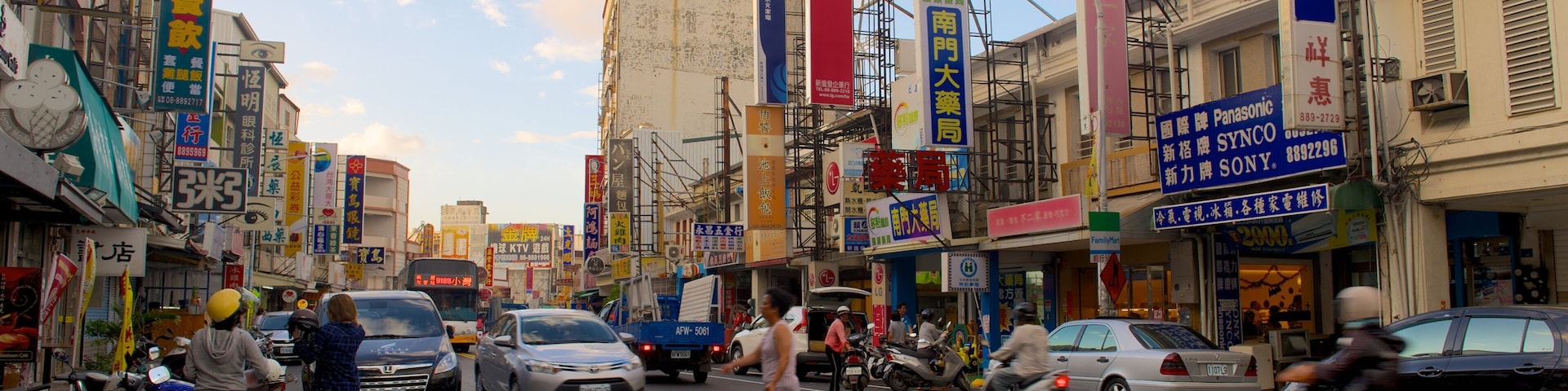 A busy urban street with various commercial signs, including Panasonic and LG.