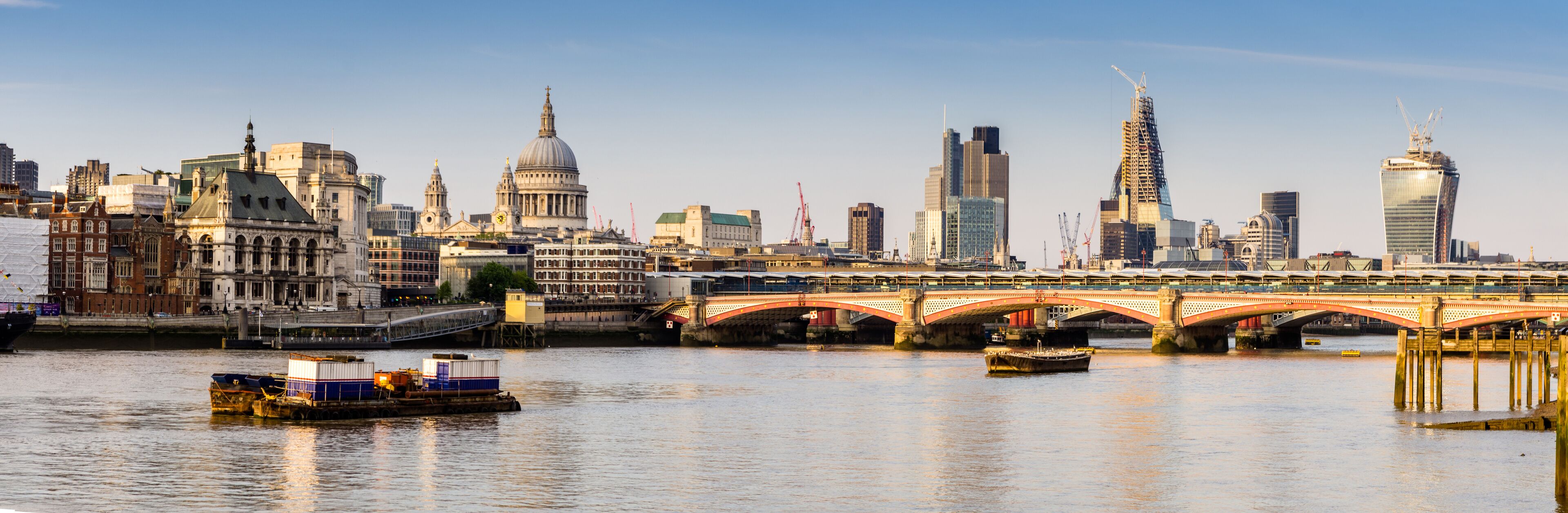 A river with boats, a bridge, and historic buildings including St. Paul's Cathedral.