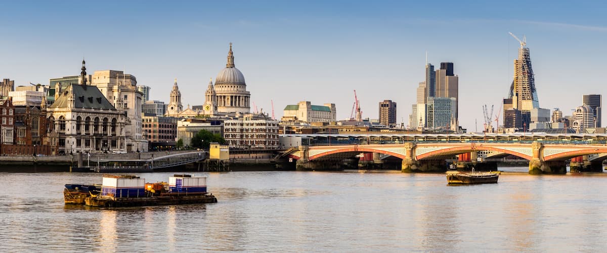 A river with boats, a bridge, and historic buildings including St. Paul's Cathedral.