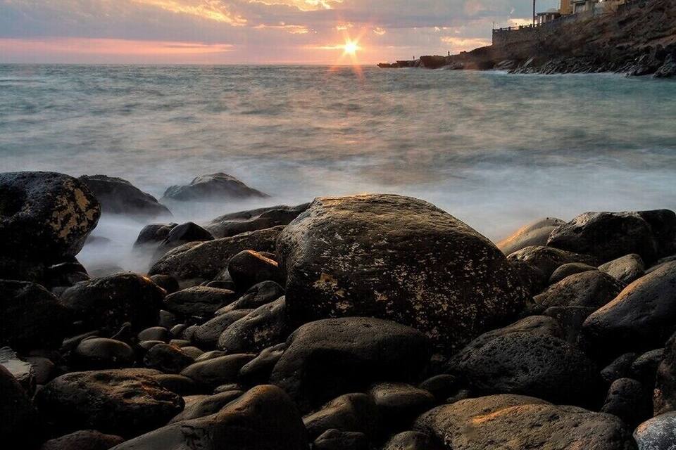 A rocky shoreline with a sunset over the ocean.