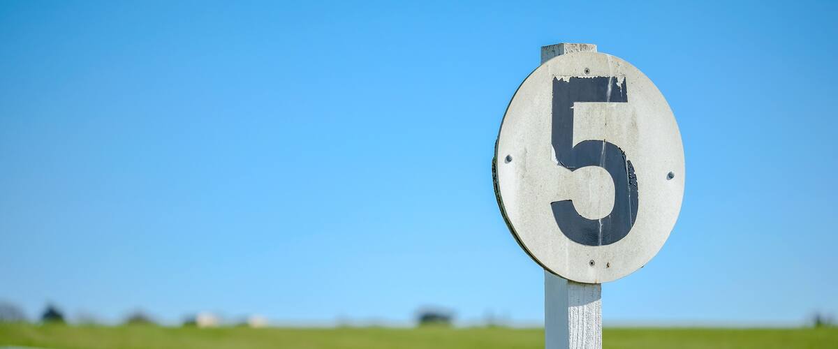 Weathered 5 furlong distance marker seen on the edge of a professional flat-racing training track in the UK.