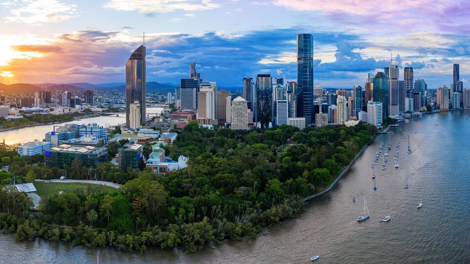 Eine Stadtansicht mit modernen Wolkenkratzern, einem Fluss und einem Park mit Booten.