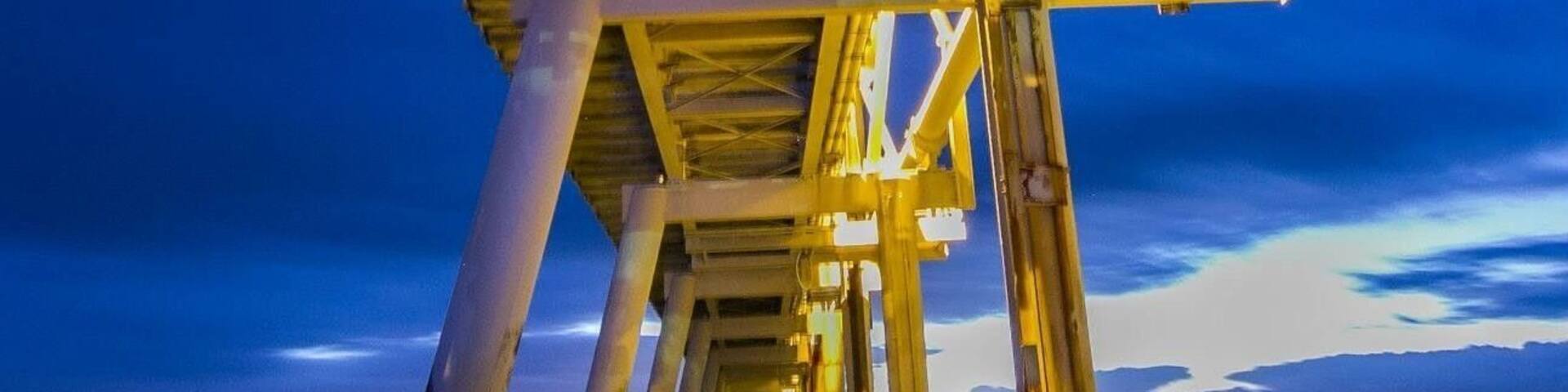 A pier structure with a blue sky and calm water.