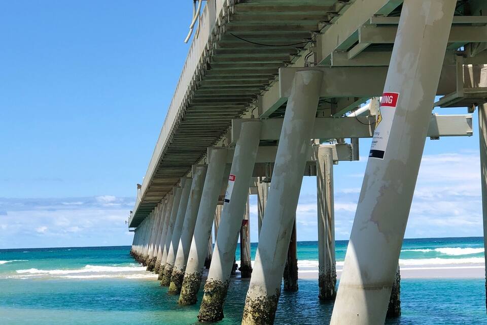 A pier extending into turquoise waters with clear skies.