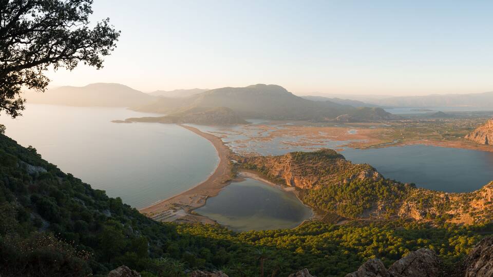 A coastal landscape with a bay, rocky outcrops, and dense greenery.