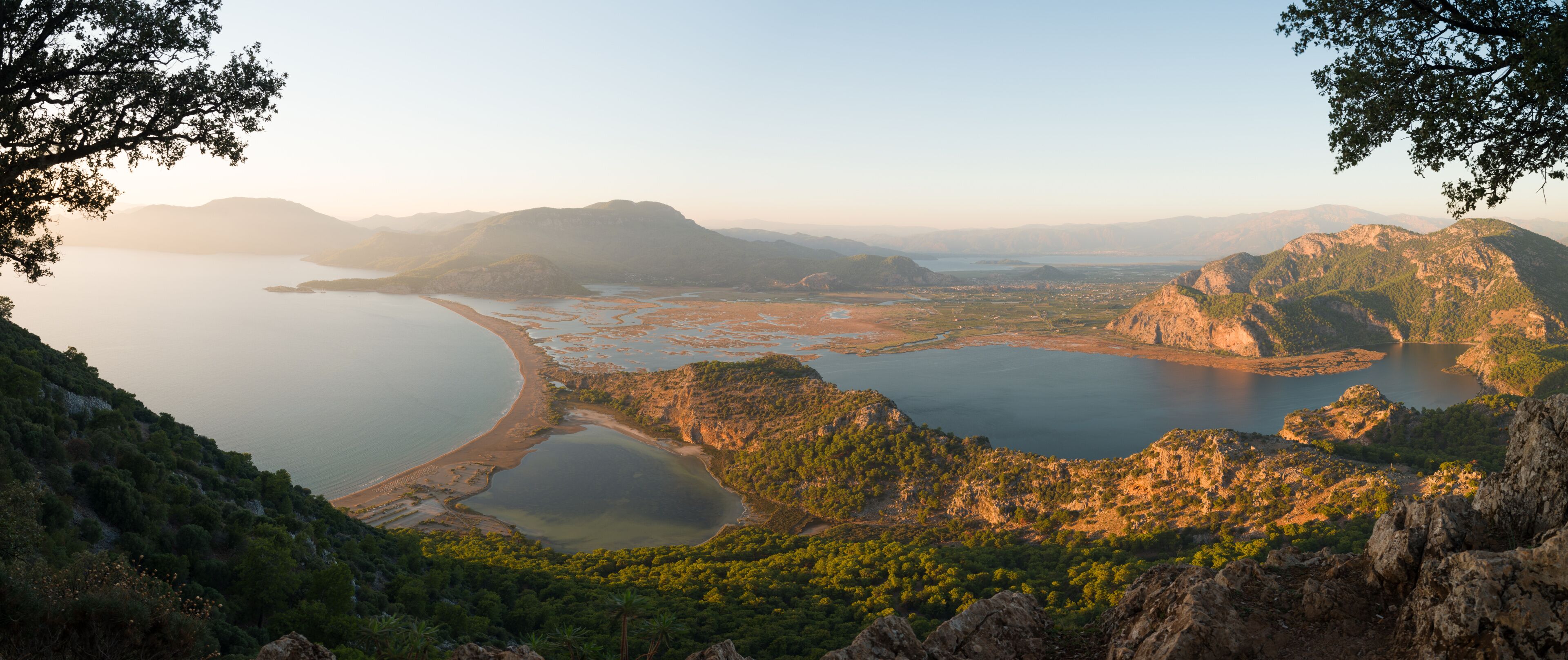 A coastal landscape with a bay, rocky outcrops, and dense greenery.