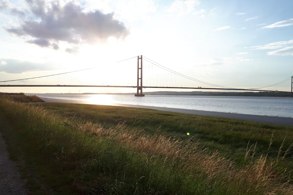 Eine Brücke über einen Fluss mit grünen Ufern.