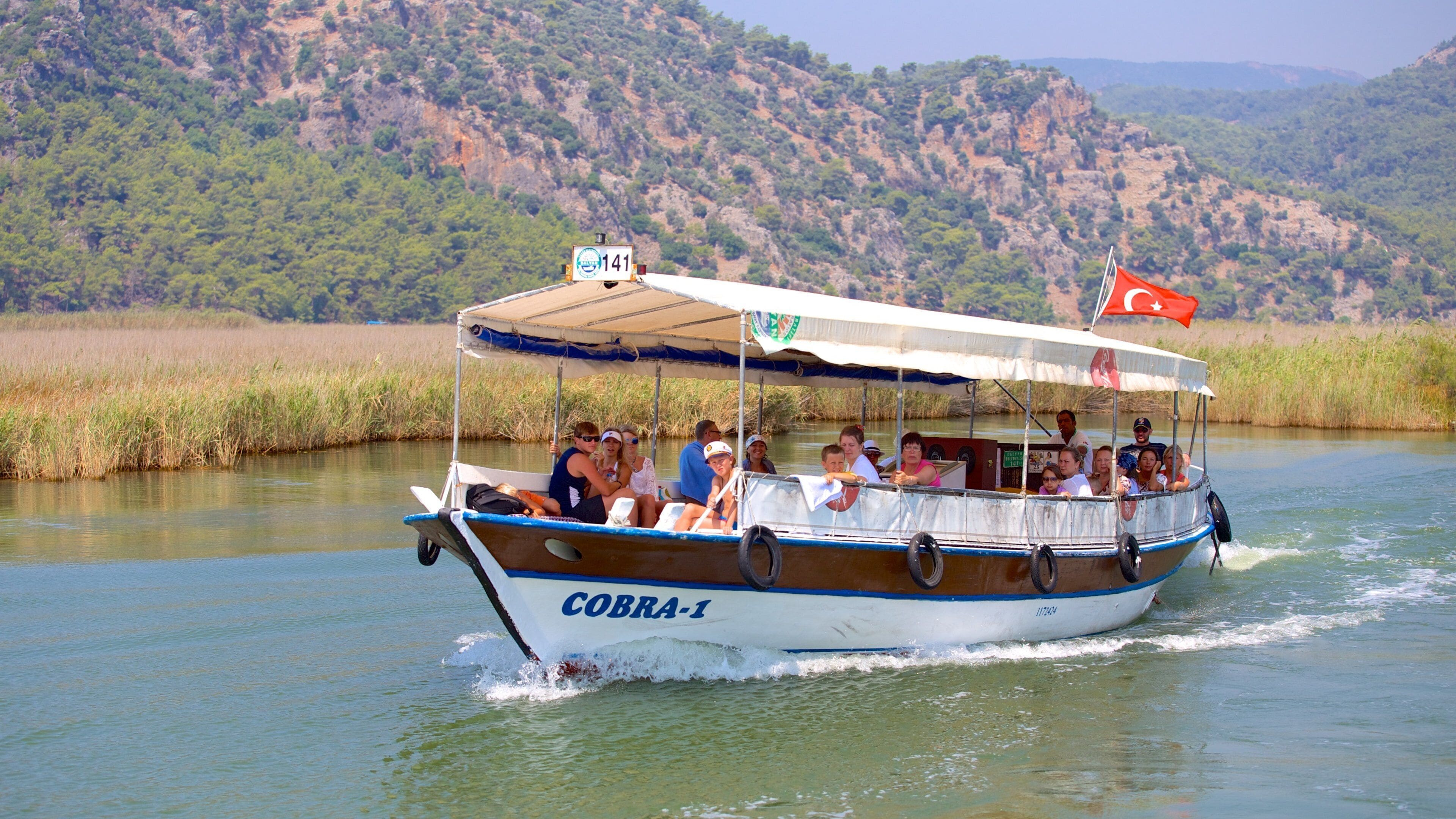 A boat named COBRA-1 on a river with a mountainous backdrop.