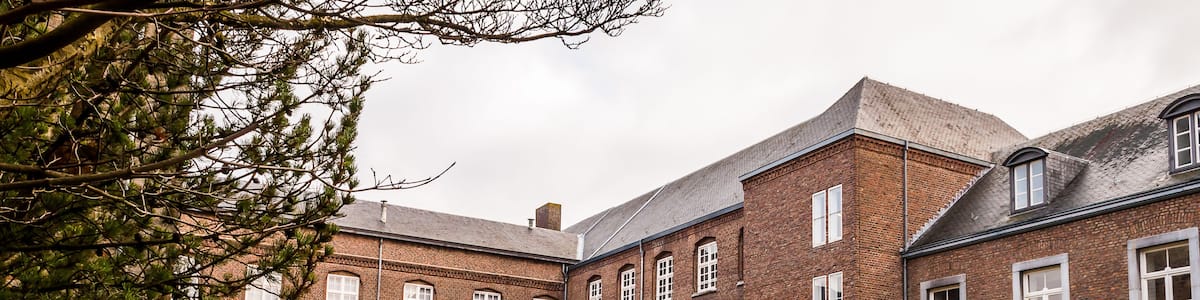 A large brick building with arched windows and a courtyard with a circular stone path.