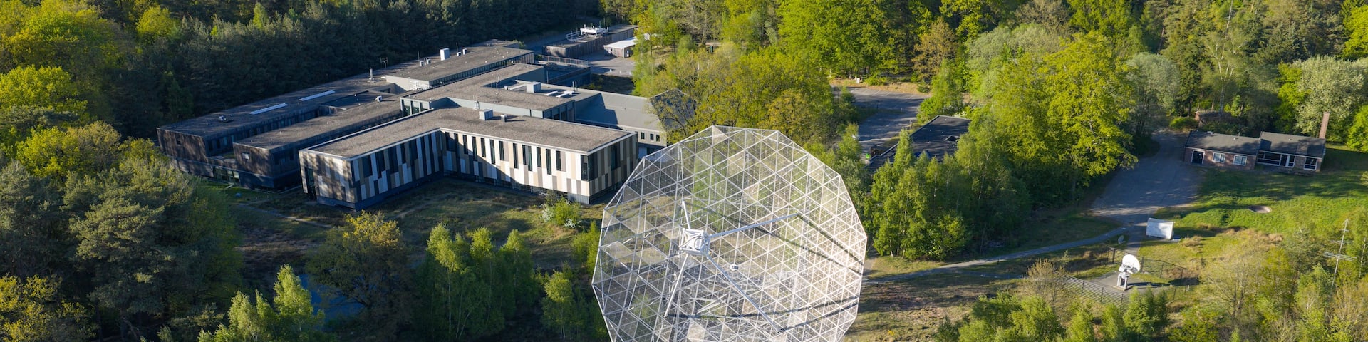 Aerial view of the Radiotelescoop surrounded by dense green forest and research facilities in Dwingeloo, Drenthe, Netherlands.