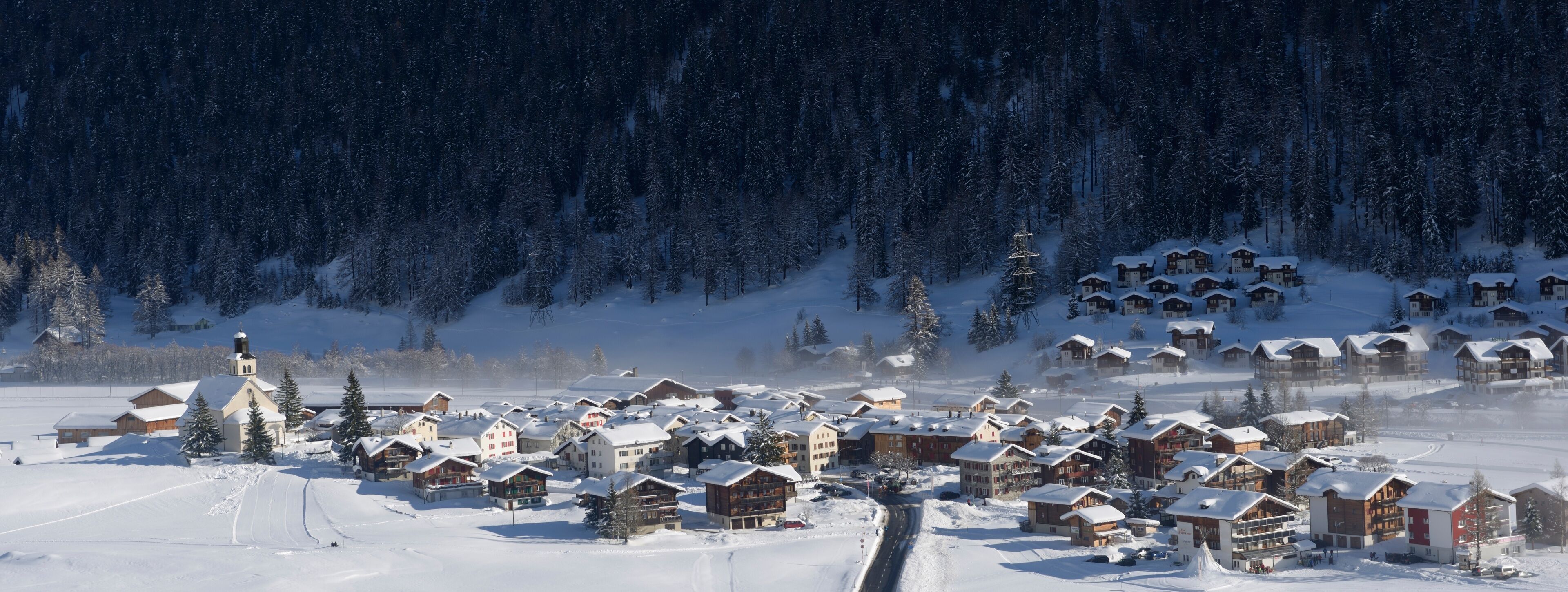 A snow-covered village with wooden houses and a church.