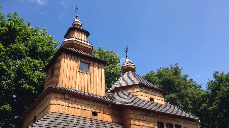 A wooden church with two domes and a cross on top.