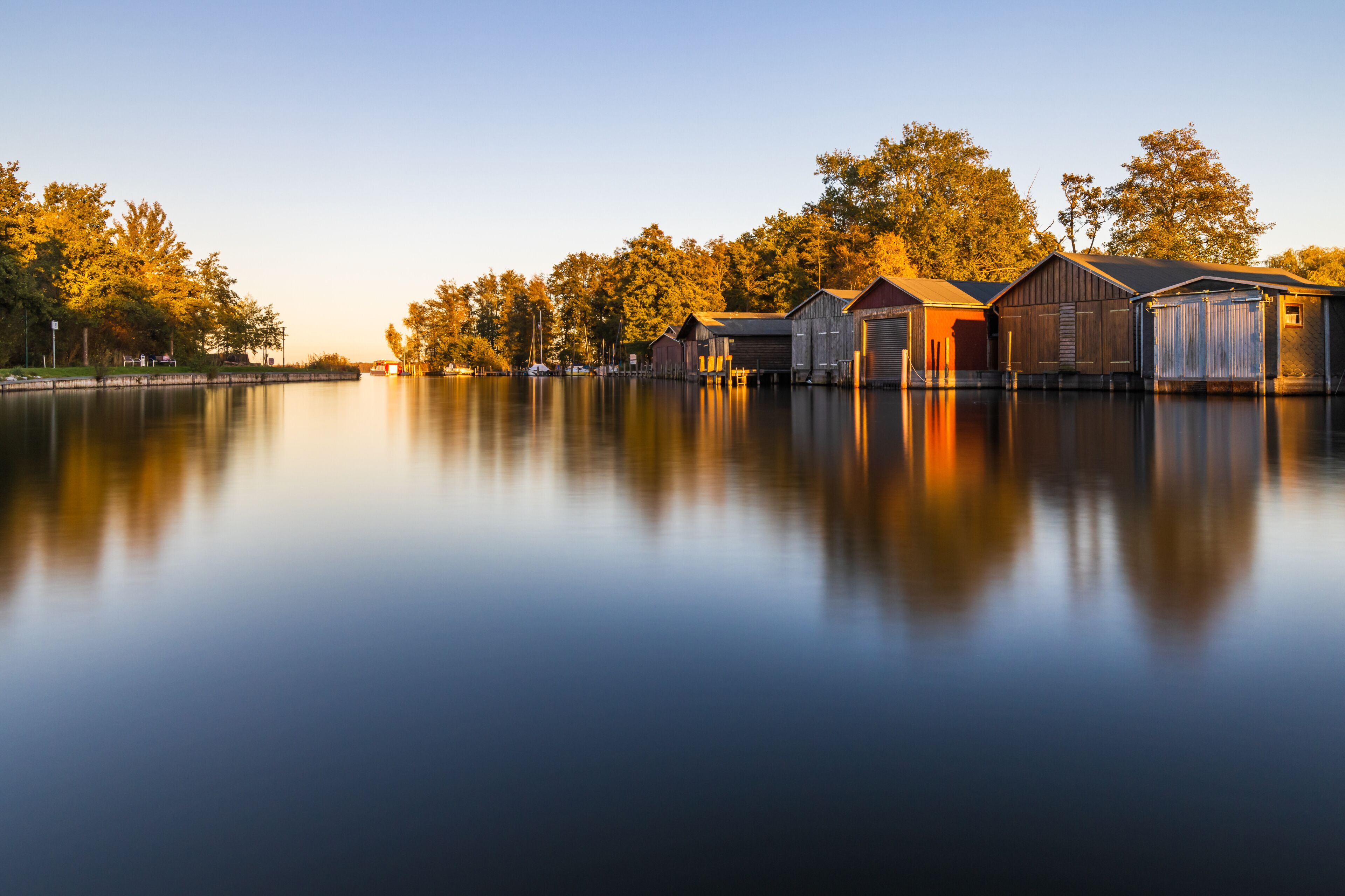 Bootshäuser in der Hafeneinfahrt von Plau am See im Herbst im Abendlicht