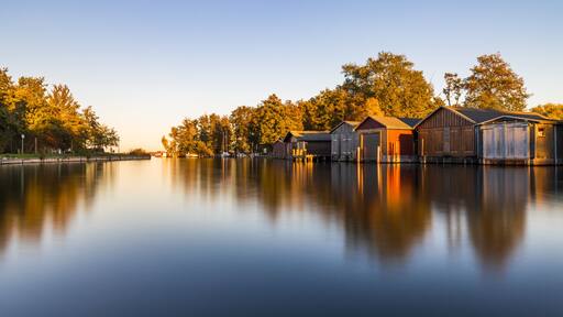 Bootshäuser in der Hafeneinfahrt von Plau am See im Herbst im Abendlicht
