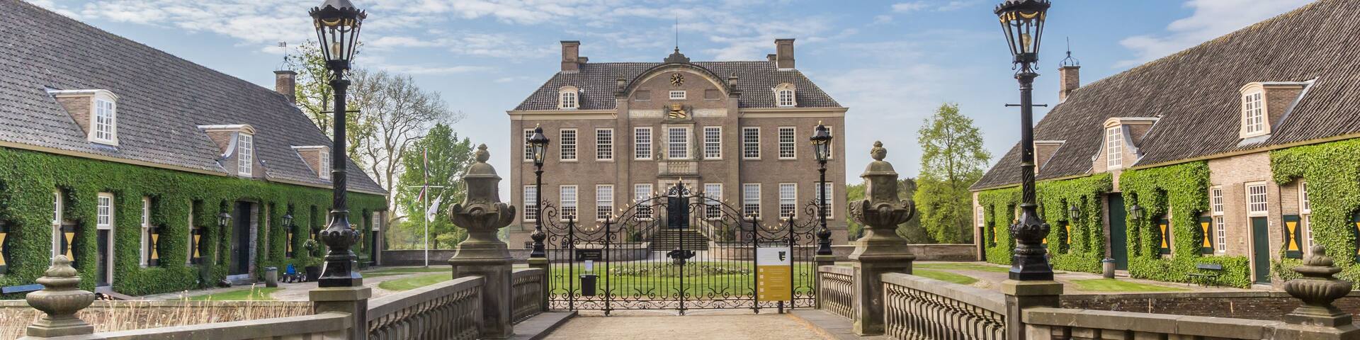 A historic building with a symmetrical facade, a central entrance gate, and ornate street lamps.