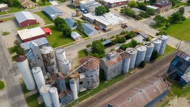 An industrial area with large storage silos, a railway line, and various buildings.