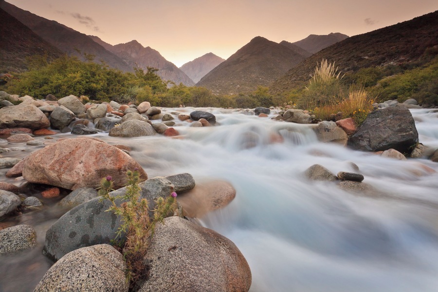 View of water stream at sunset with sun setting behind Andes Mountain rang located near Tunuyan, Mendoza, Argentina.