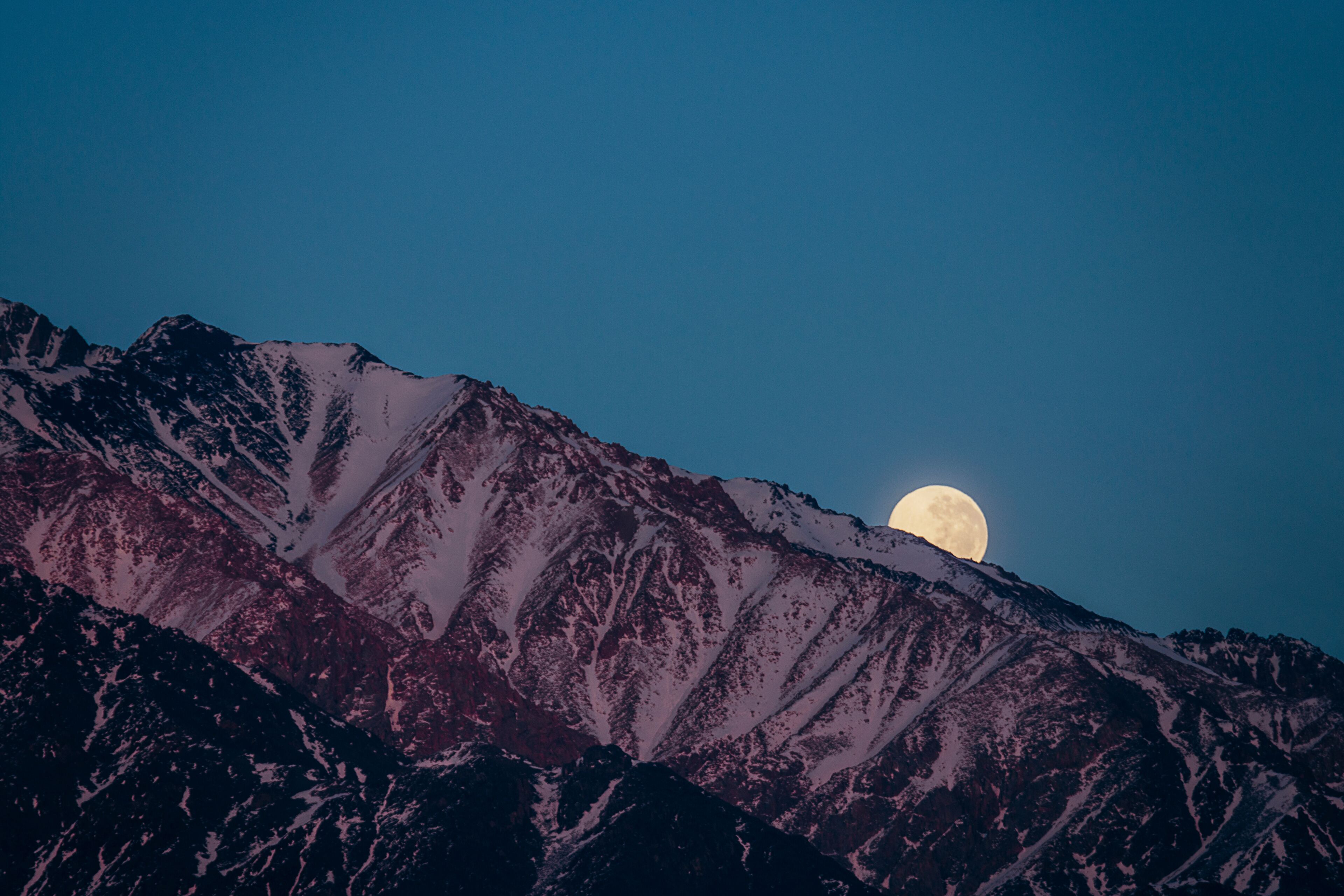 full moon hiding behind the andes mountain range in mendoza argentina