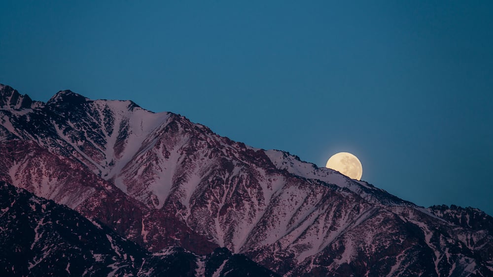 Une chaîne de montagnes sous une pleine lune.