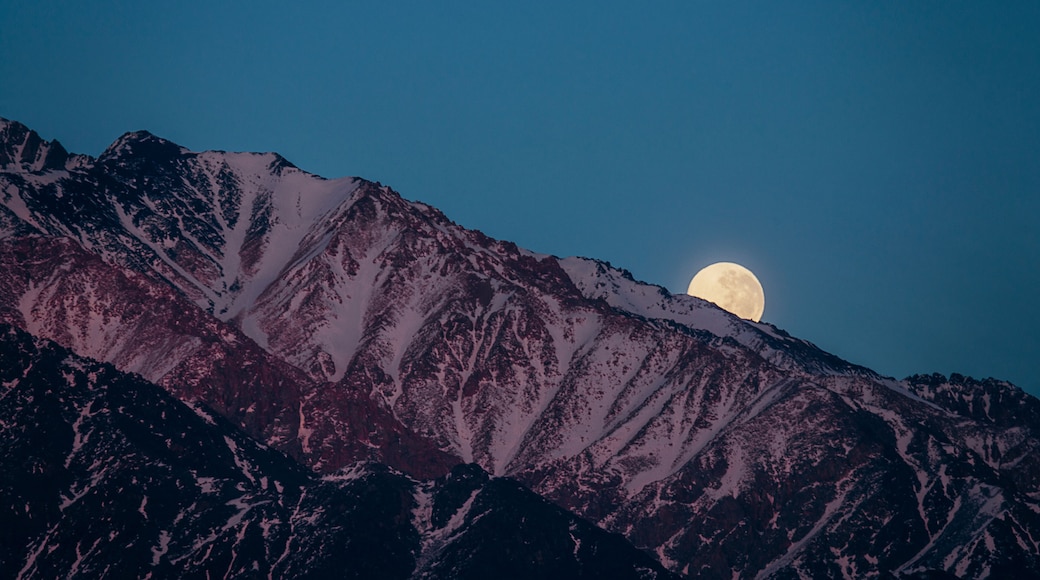 full moon hiding behind the andes mountain range in mendoza argentina