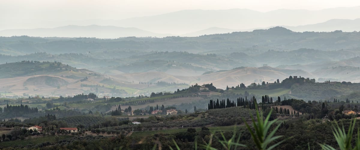 Rolling hills, vineyards, and scattered buildings in a hilly landscape.