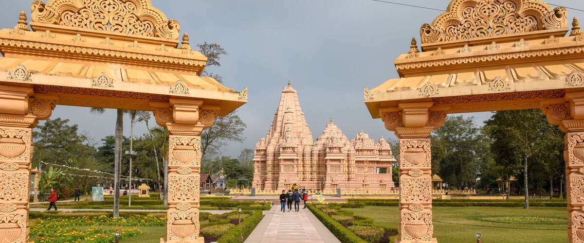 A temple with intricate carvings, a central pathway, and a well-maintained garden.