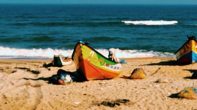 Two colorful boats on a sandy beach with the ocean in the background.