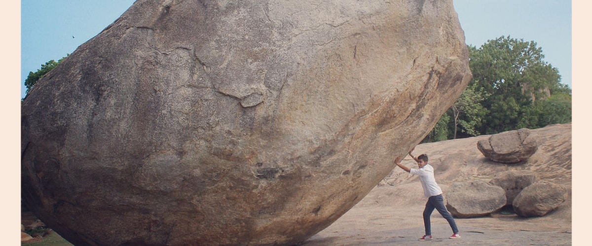 This is a photo of me trying to push 'The Krishna's butterball.' The stone is called Krishna's butterball because even when its shape is a circular one still it manages to balance on a inclined plane and even after enormous efforts the stone was not be able to rolled down the surface.