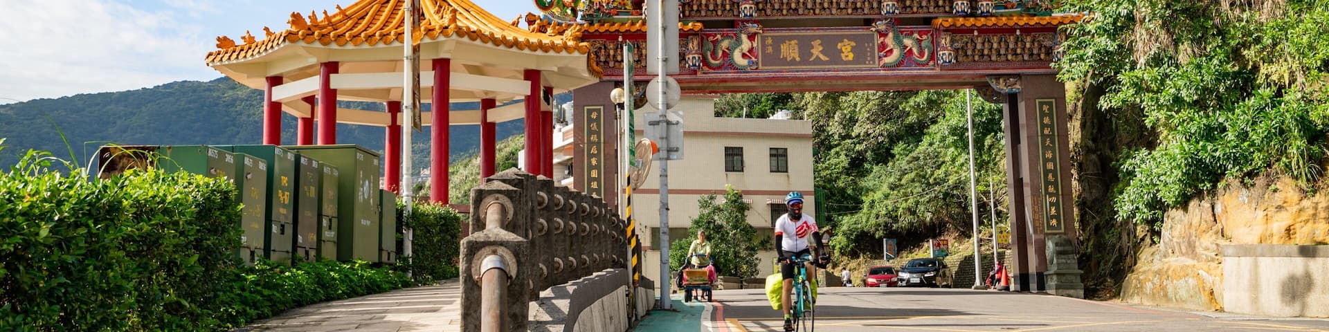 A traditional Chinese gate with intricate dragon decorations, a pagoda, and lush greenery.