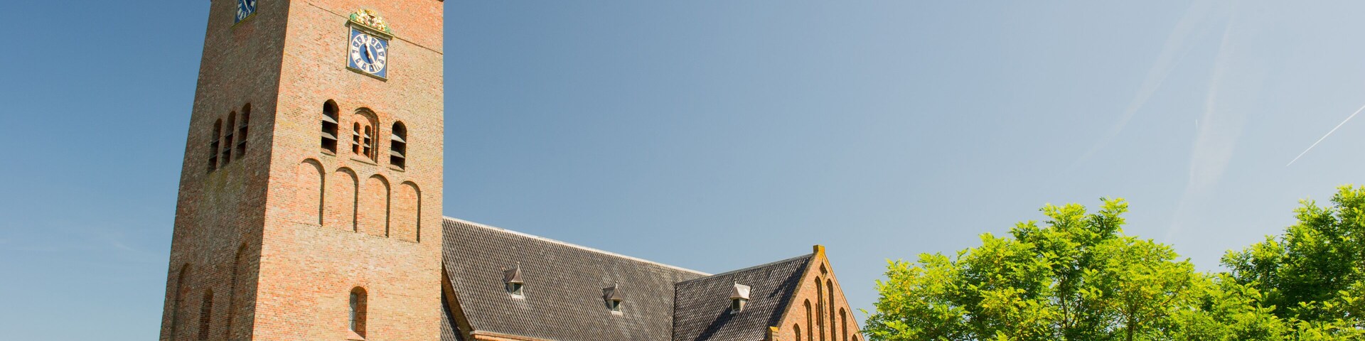 A large brick church with a tall tower and a clock.