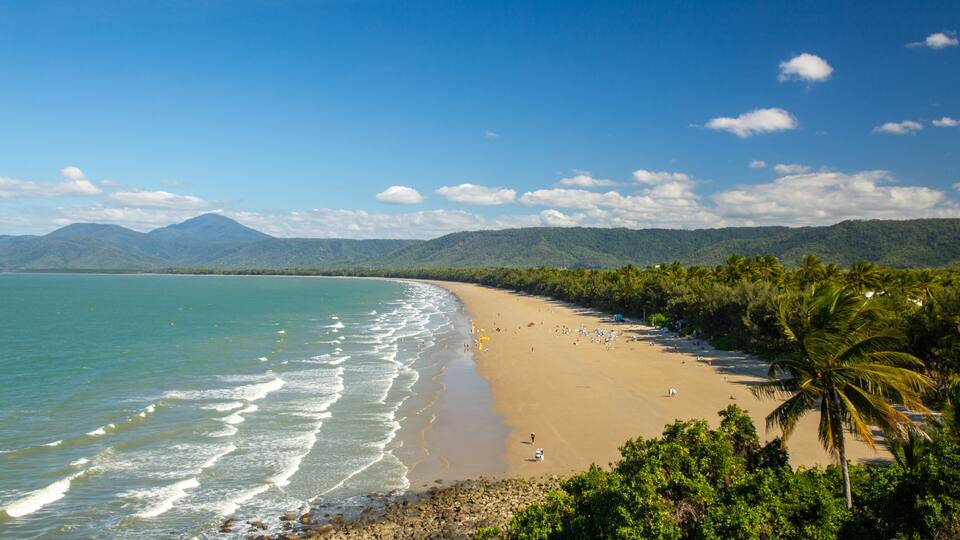 A tropical beach with clear turquoise waters, a sandy shore, and lush greenery.