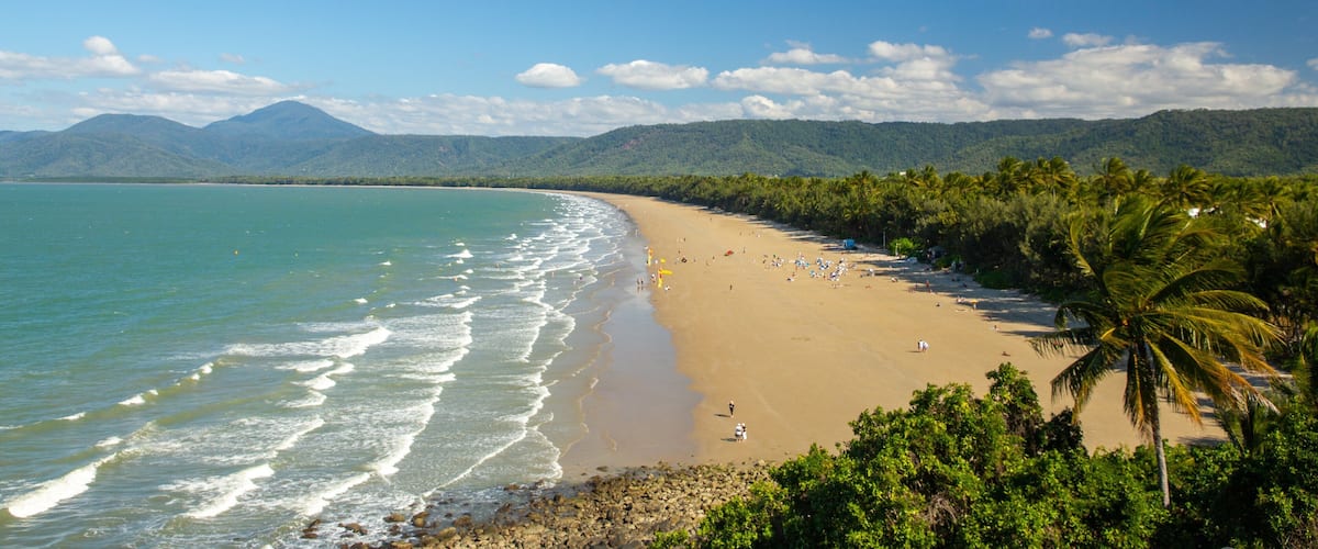 A tropical beach with clear turquoise waters, a sandy shore, and lush greenery.