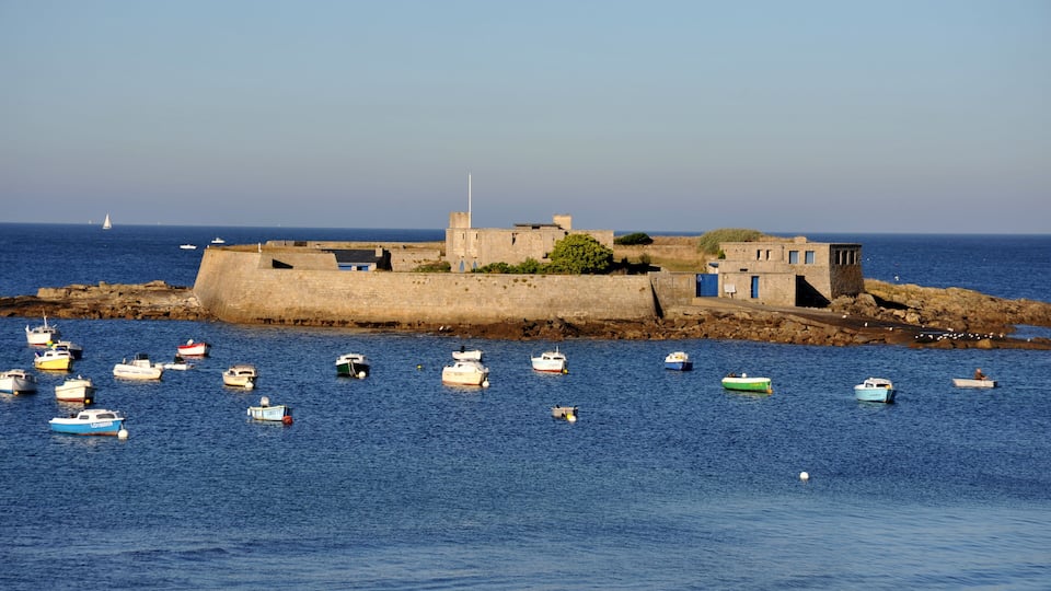 A coastal fortification with a clear view of the sea, surrounded by small boats.
