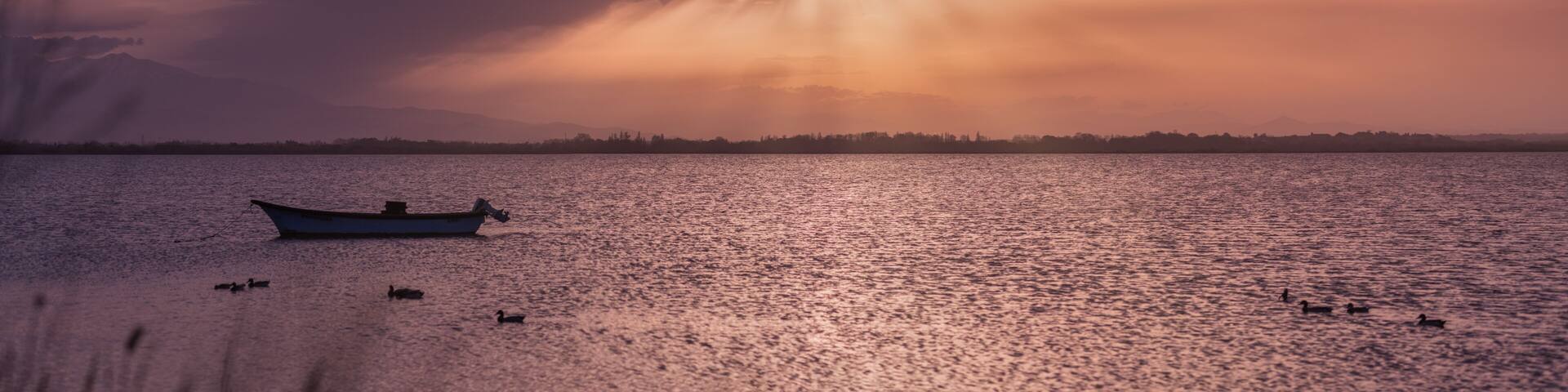 boat on the background of the sunset with rays breaking through the clouds on proud in Canet-en-Roussillon